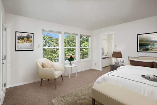 A bedroom with a large bed, a chair, and a painting on the wall.
