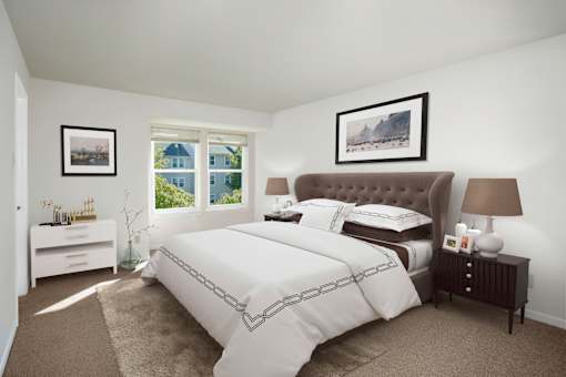 A bedroom with a large bed and a window overlooking a blue house.