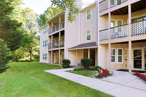 A building with a balcony and a lawn in front.
