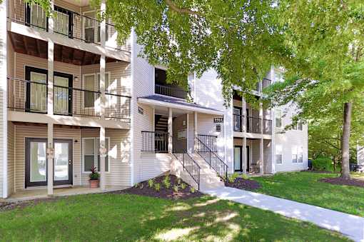 A white apartment building with a tree in front.