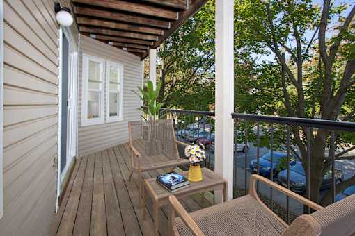 A balcony with a table and chairs overlooking a parking lot.