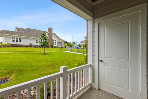 A white door is on the porch of a house.