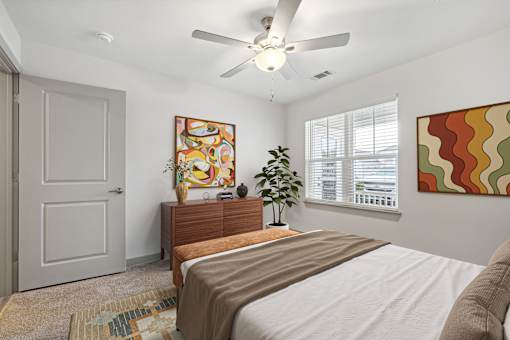 A bedroom with a bed, dresser, and a ceiling fan.