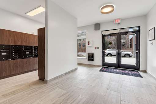 A hallway with a black door and a black mat on the floor.