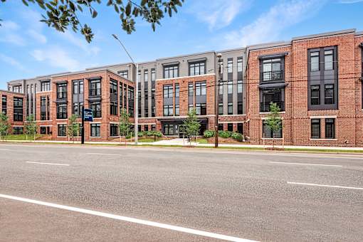 A row of red brick apartment buildings with trees in front.