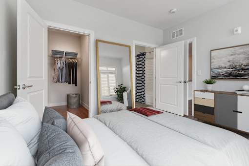 A bedroom with a large bed and a wardrobe with clothes hanging.