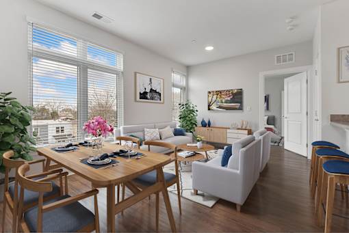 A dining room with a table set for six and a couch with blue cushions.