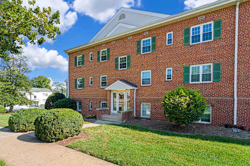 A red brick building with green shutters and a white door.