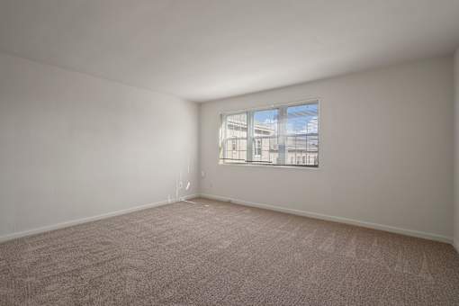 Empty room with carpeted floor and a window.