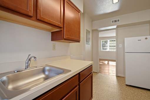 A kitchen with a white fridge and brown cabinets.