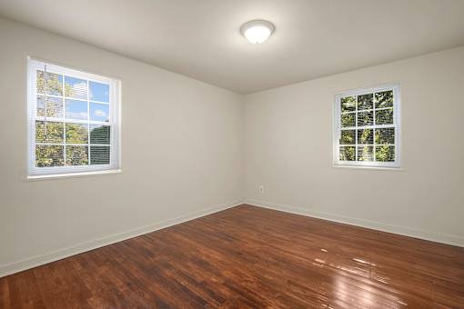 A room with wooden floors and two windows.