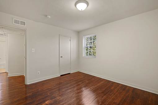A room with wooden floors and a window with a view of trees.