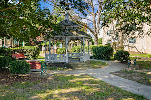 A gazebo is surrounded by green bushes and trees.