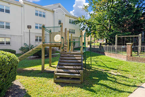 A playground with a slide and a green fence.