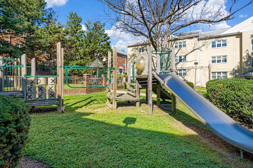 A playground with a slide and a green gate.