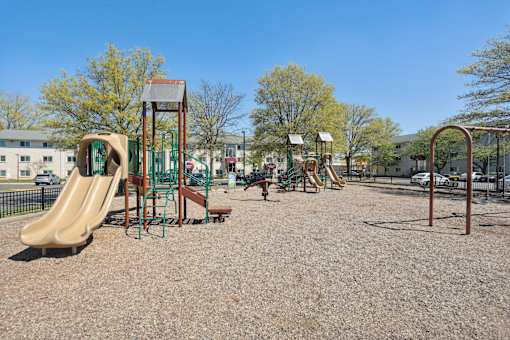 A playground with a slide, swings, and a seesaw.