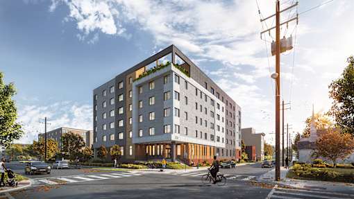 A modern building with a green roof is situated on a street corner with a cyclist passing by.