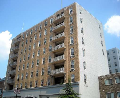 A tall building with balconies on the second floor.