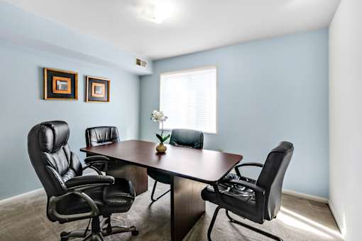 A conference room with a table and four chairs.