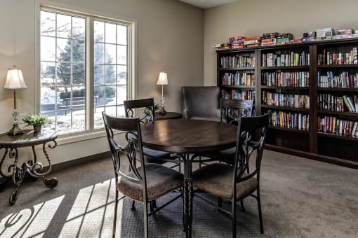a library with a table and chairs in front of a window