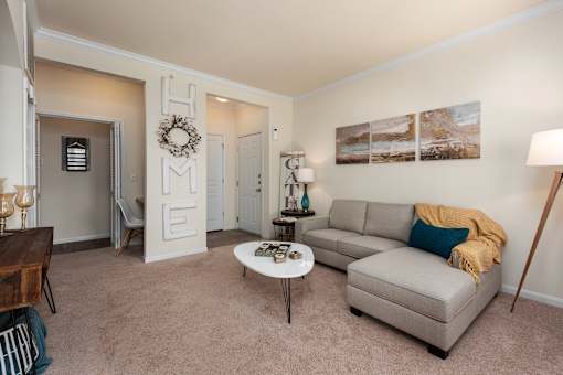 A living room with a grey couch, a coffee table, and a wreath on the door.