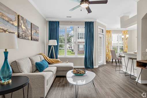 A living room with a couch, a table, and a ceiling fan.