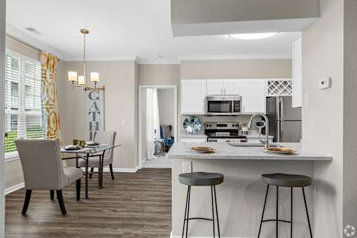 A kitchen with a dining table and chairs.