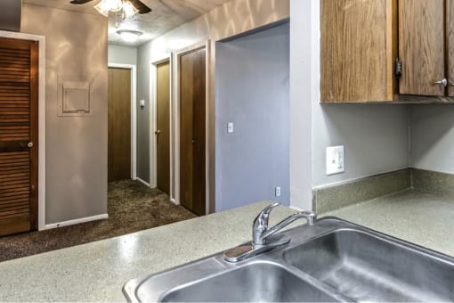 a kitchen with a sink and a hallway with closets