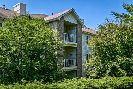 an apartment building with trees and bushes in front of it