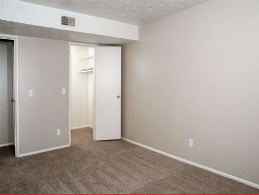an empty room with a carpeted floor and a closet