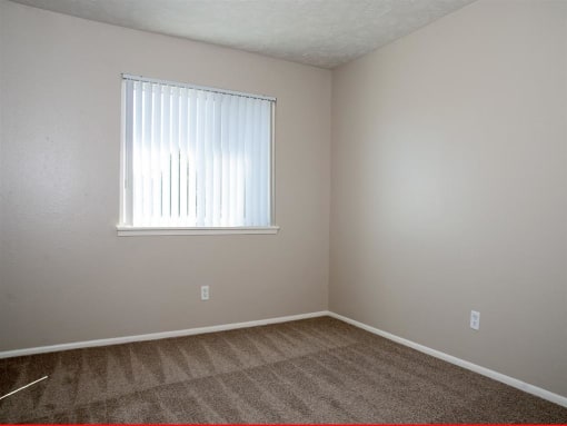 an empty room with a window and carpet