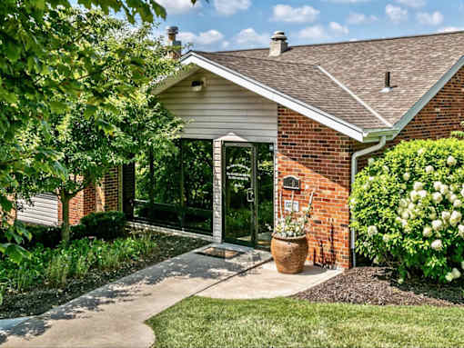 a walkway in front of a brick house with a patio and a glass door