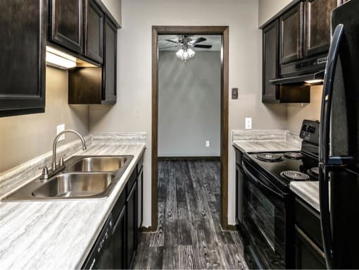 a kitchen with black cabinets and a sink and a door to a hallway