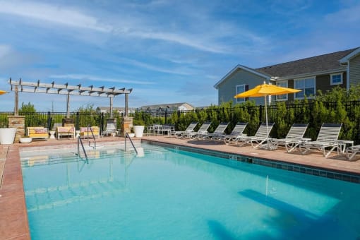 a swimming pool with chairs and a house in the background