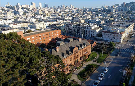 A large building with a red roof is in the center of a city.