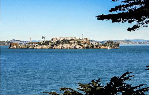 A large building sits on a cliff overlooking a body of water.