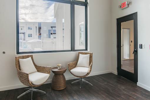 Two chairs and a table are in a room with a window.