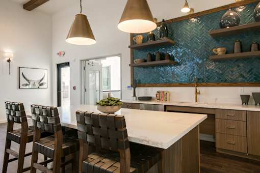 A kitchen with a white counter top and brown chairs.