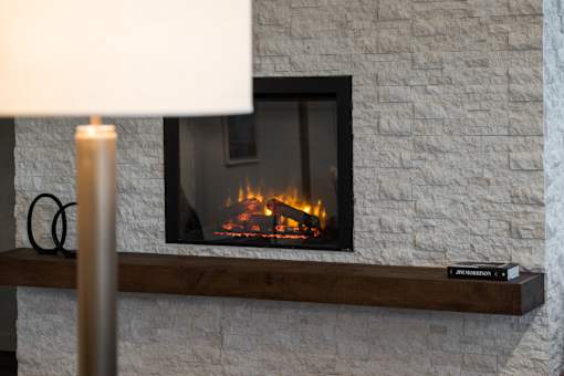 A fireplace with a fire burning inside and a white lamp above it.