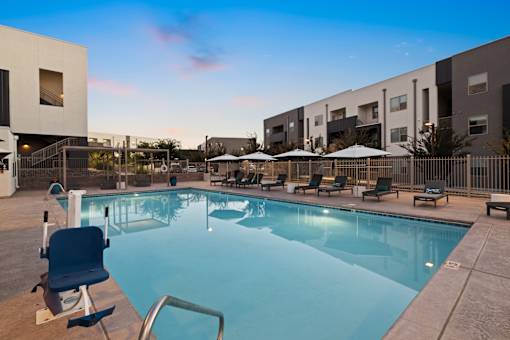A swimming pool surrounded by chairs and umbrellas in a residential area.