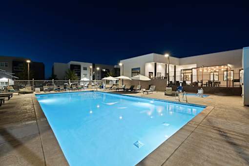 A large swimming pool with a wooden deck and lounge chairs.