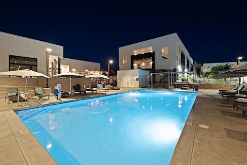A large swimming pool in front of a building at night.