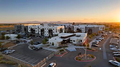 A parking lot with cars and a building in the background during sunset.