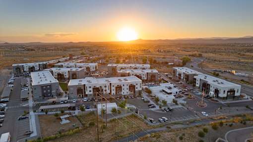 A sunset view of a parking lot with several buildings in the background.
