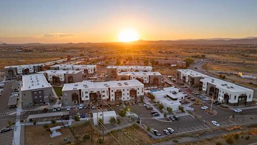 A sunset view of a residential area with houses and parked cars.