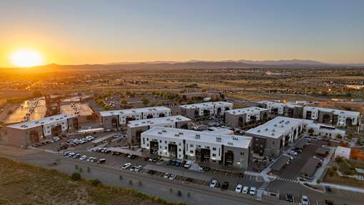 A sunset view of a parking lot with several cars and a building with the number 220.