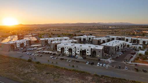 A sunset view of a parking lot with cars and buildings.
