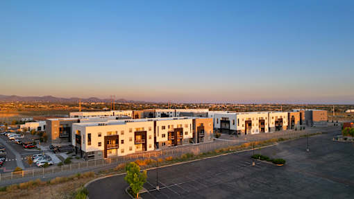 A large, modern building complex with a parking lot in front.