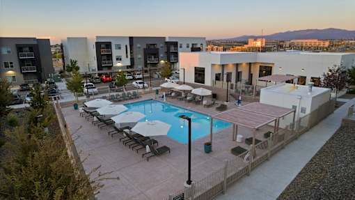 A swimming pool surrounded by lounge chairs and umbrellas in a residential area.