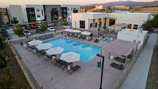 A pool surrounded by lounge chairs and umbrellas.